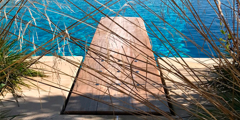 Trampolín de madera Mikel Tube encastrado a la misma altura que la piedra de coronación de la piscina